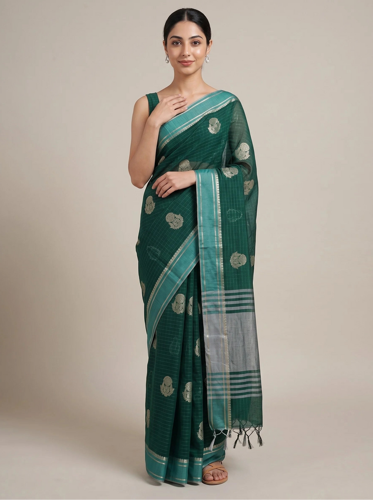 A woman modeling a dark green woven saree with metallic silver motifs and a striped border, standing against a solid beige studio background.