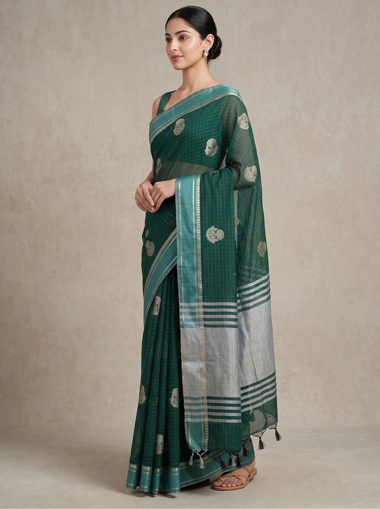A woman modeling a dark green saree with silver and white stripes, floral motifs, and a wide silver border, set against a neutral beige studio backdrop.