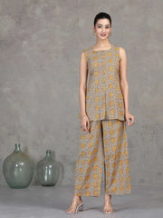 Woman wearing a sleeveless top and wide-leg pants with a pattern against a gray background