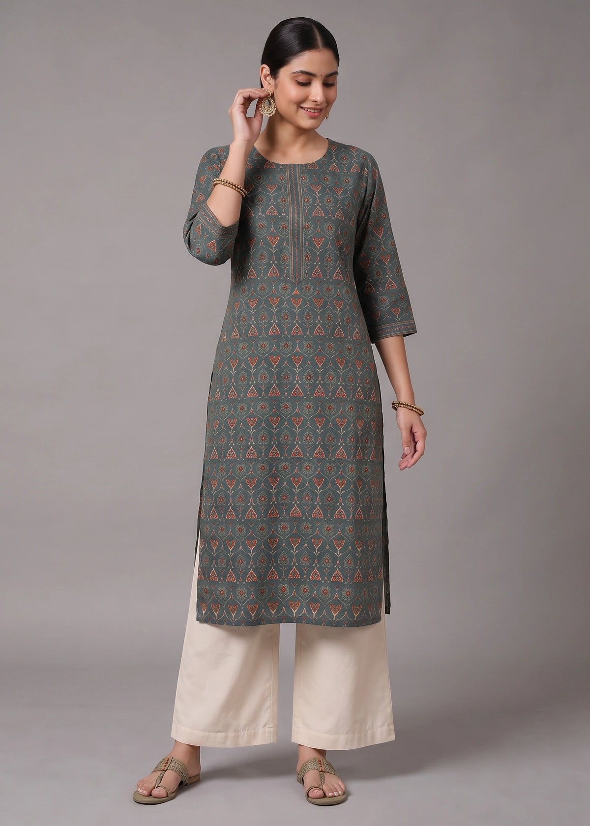 A woman modeling a dark gray three-quarter sleeve kurta with a colorful geometric pattern, paired with cream-colored wide-leg pants, against a solid gray studio background.