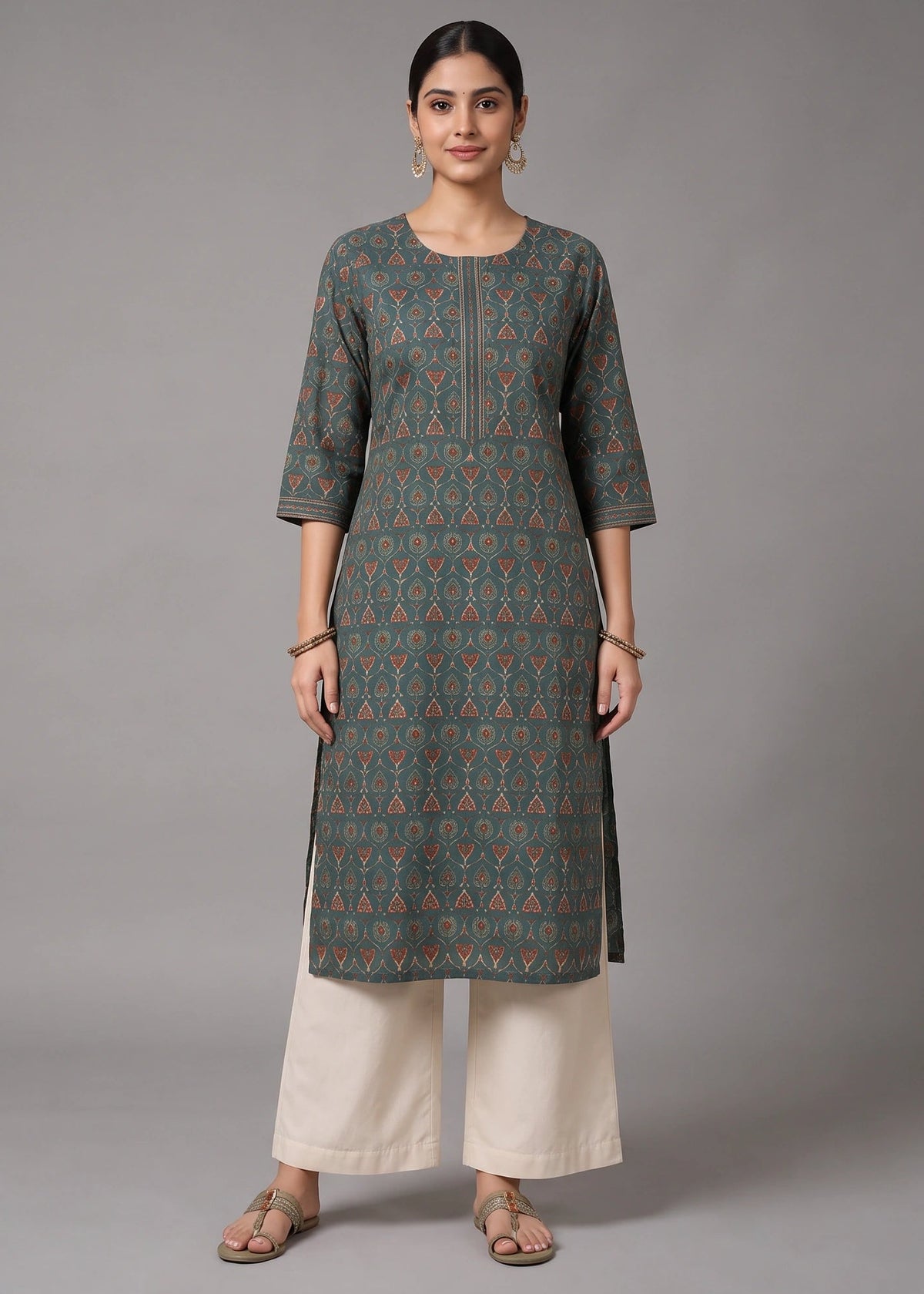 A woman modeling a dark gray-green printed kurta with orange and blue geometric patterns, paired with cream-colored wide-leg pants, against a solid gray studio background.