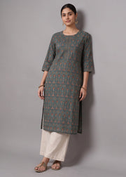 A woman modeling a three-quarter sleeve kurta with a gray base and orange geometric print, paired with off-white pants, against a solid gray studio background.