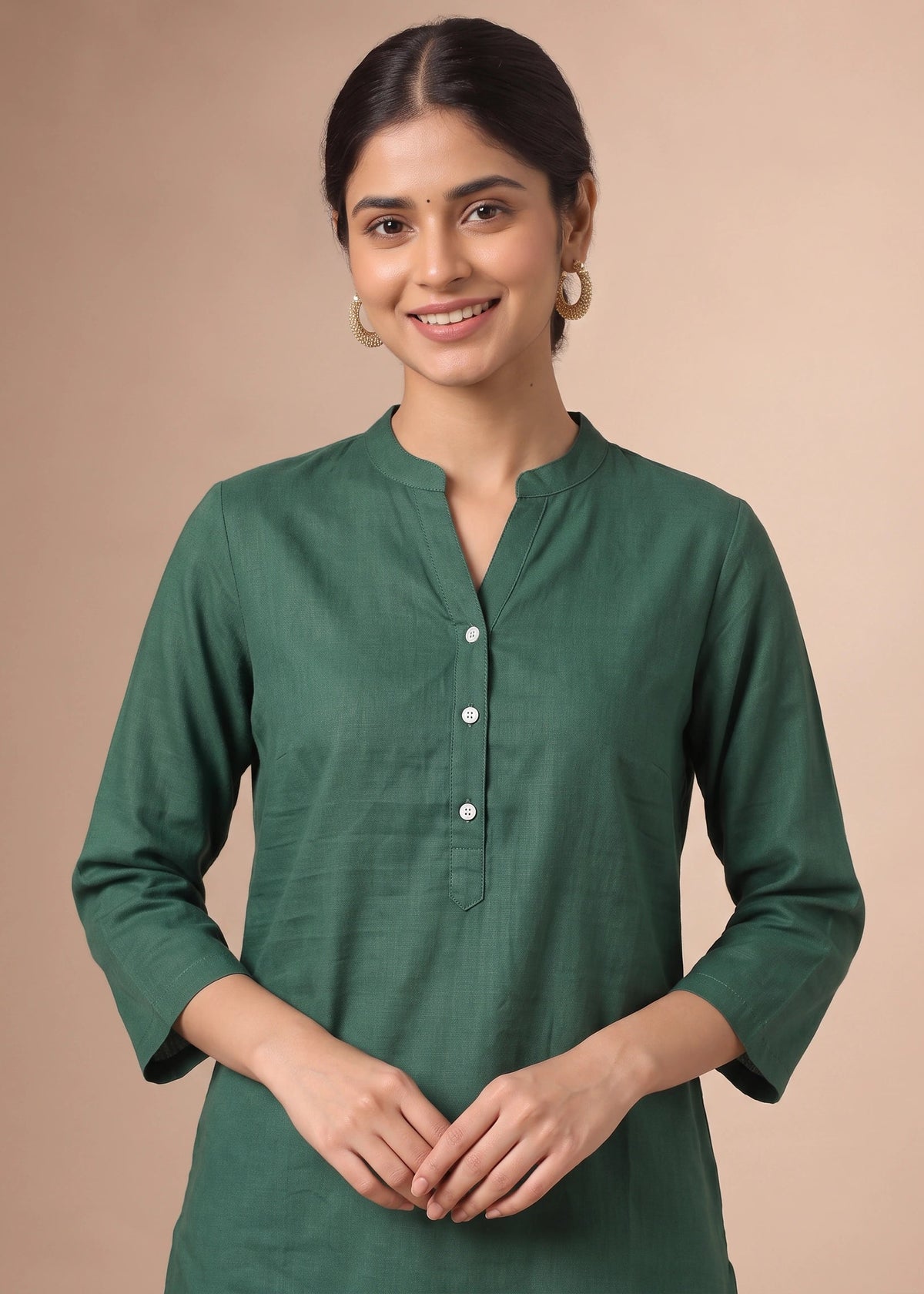 A woman wearing a dark green three-quarter sleeve kurta with a split neckline and white buttons, standing against a solid beige background.