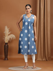 Woman wearing a blue dress with white polka dots against a brown background