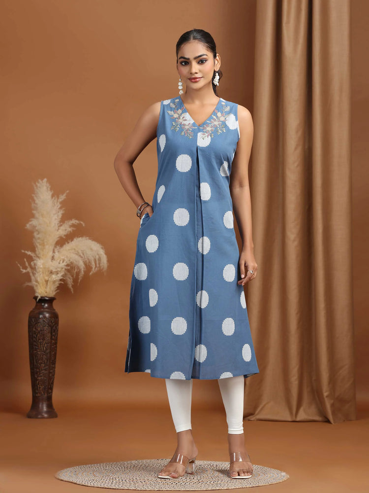 Woman wearing a blue dress with white polka dots against a brown background