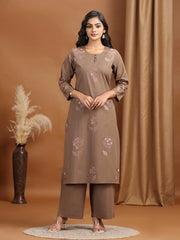 Woman wearing a brown kurta with floral embroidery against a brown background