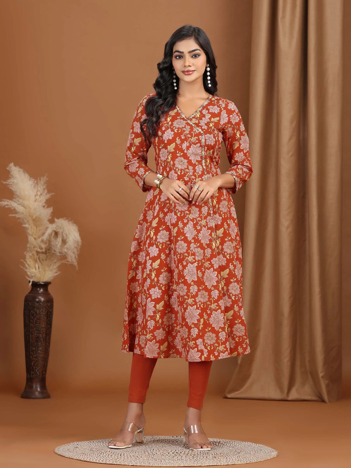 Woman wearing a red floral dress standing against a brown background