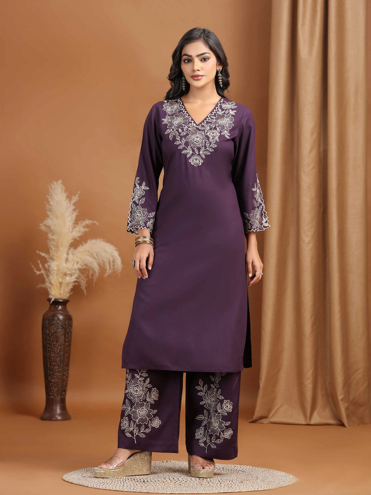 Woman wearing a purple embroidered outfit against a brown background