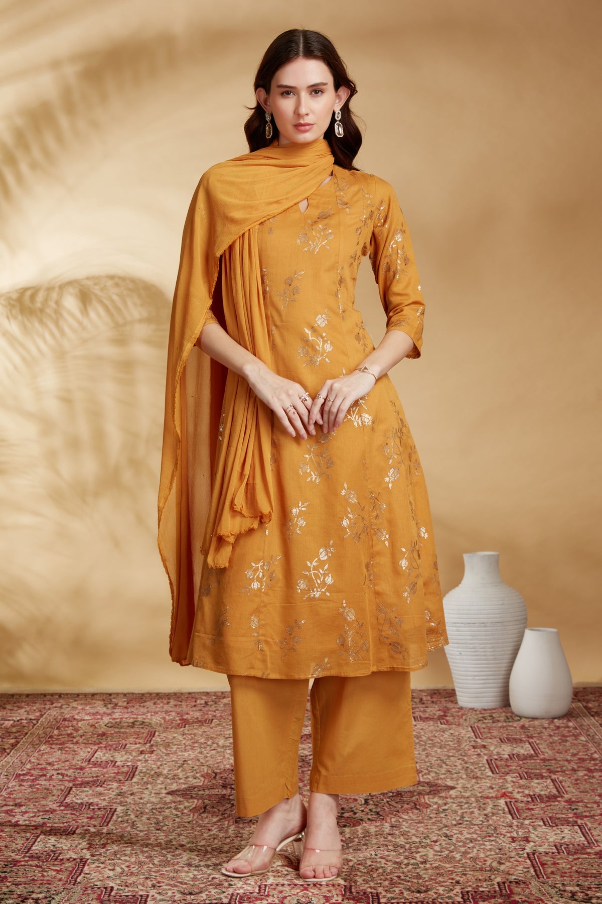 Woman wearing a mustard yellow traditional outfit with a plain background