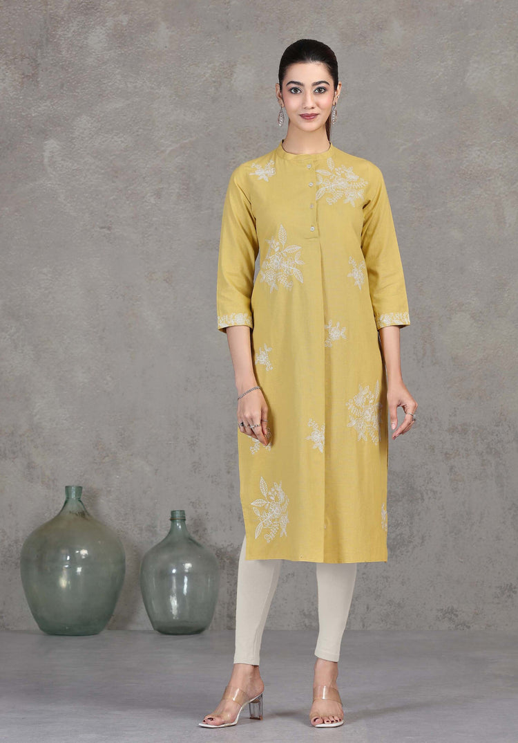 Woman wearing a yellow kurta with floral patterns against a gray background