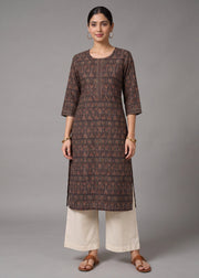A woman modeling a brown printed kurta with three-quarter sleeves, paired with off-white wide-leg pants and brown sandals, against a solid gray studio background.