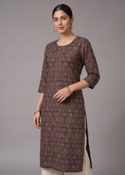 A woman modeling a brown printed kurta with three-quarter sleeves and side slits, paired with off-white pants, against a solid gray studio background.