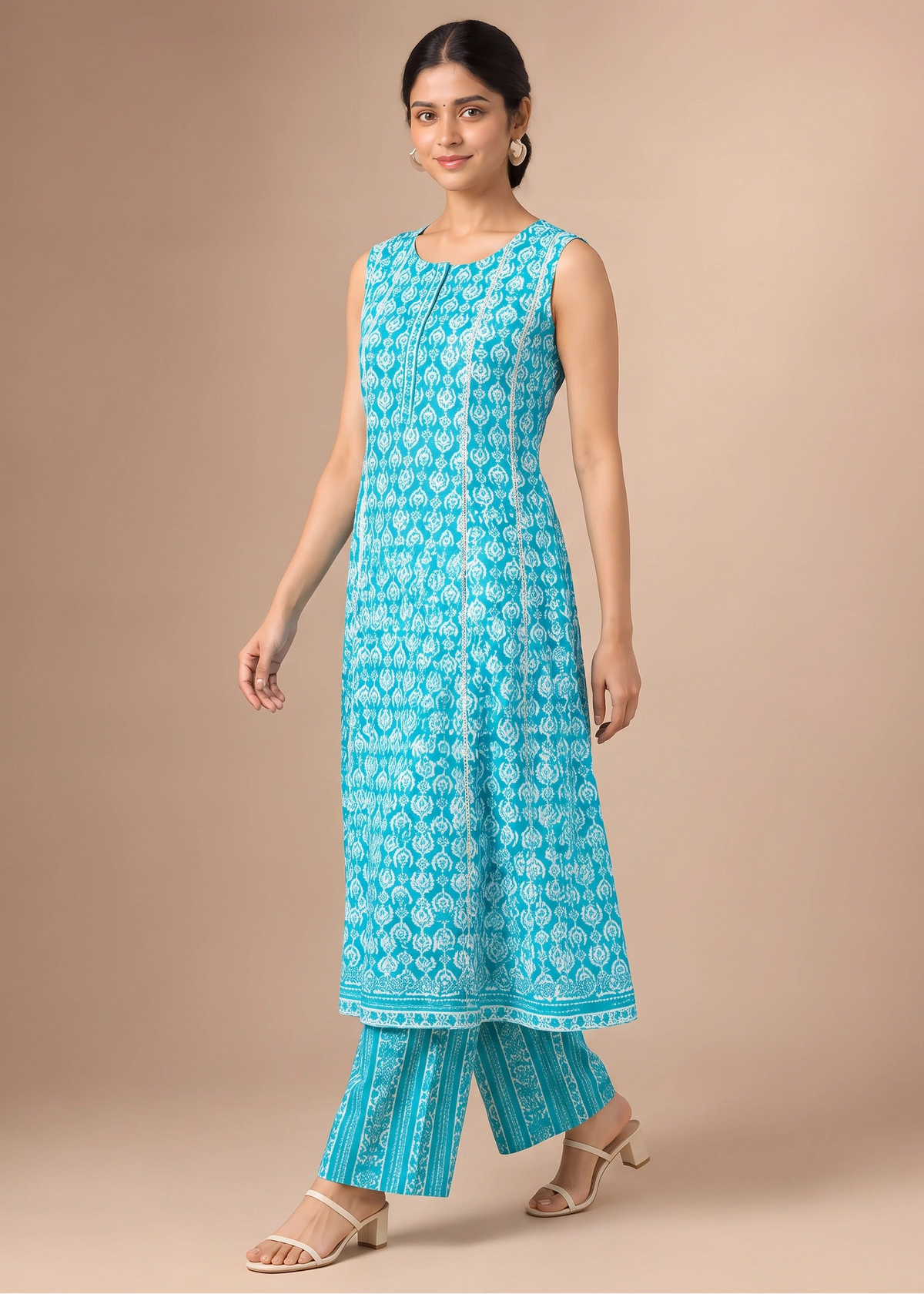 A woman modeling a turquoise blue printed kurta and matching wide-leg pants set against a solid beige studio background.