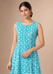 A woman modeling a sleeveless turquoise blue and white printed kurta against a solid beige studio background.
