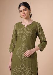 A woman modeling an olive green kurta with beige embroidered patterns, set against a solid beige background.