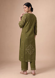 A woman modeling an olive green kurta set with beige embroidery, shown from the back against a solid beige studio background.