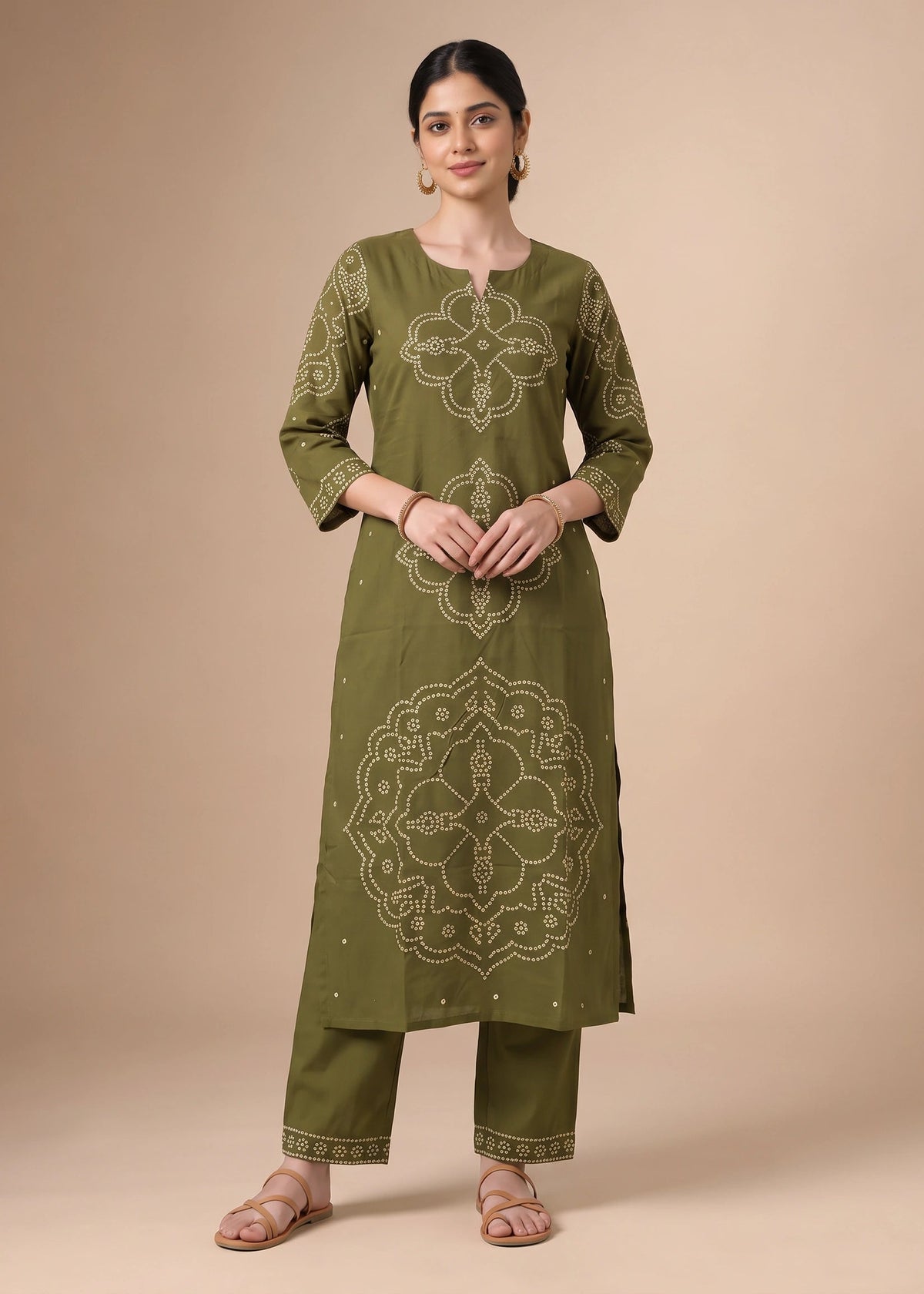 A woman modeling an olive green kurta set with beige geometric and floral embroidery, paired with matching pants, against a solid beige studio background.