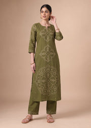 A woman modeling an olive green kurta set with beige geometric embroidery, paired with matching pants, against a solid beige studio background.