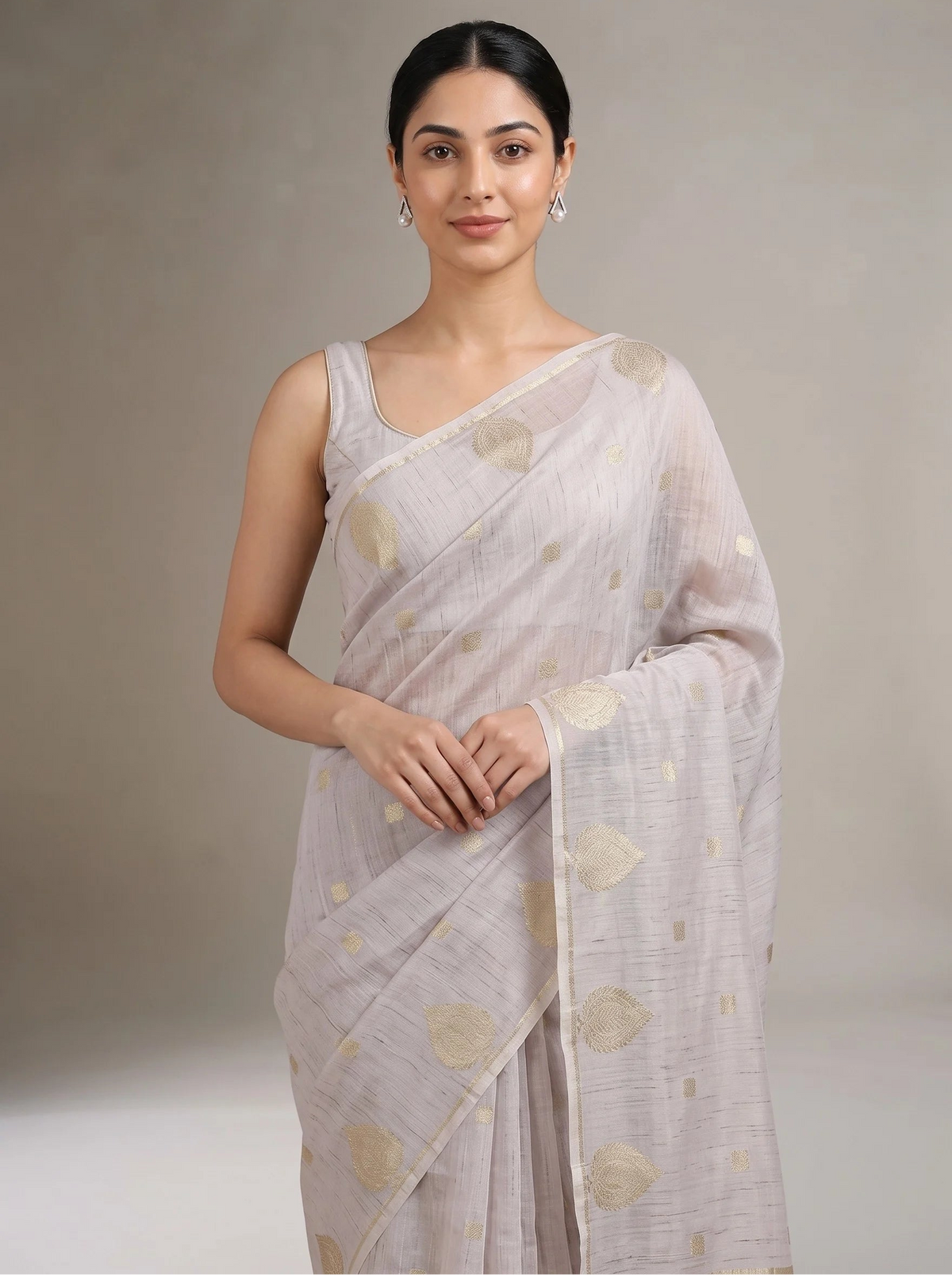 A woman modeling a lilac purple saree with metallic gold motifs, set against a neutral beige studio background.