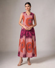 A woman modeling a sleeveless V-neck maxi dress with a pink, purple, and orange ikat pattern, standing against a neutral studio background.