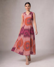 A sleeveless V-neck midi dress with a pink, orange, and purple ikat pattern, modeled against a neutral studio background.