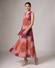 A woman modeling a sleeveless, V-neck maxi dress with a pink, orange, and purple ikat-inspired pattern against a neutral studio background.