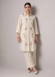 A woman models a cream-colored kurta set with pink floral embroidery, paired with matching cream trousers, against a neutral gray studio background.